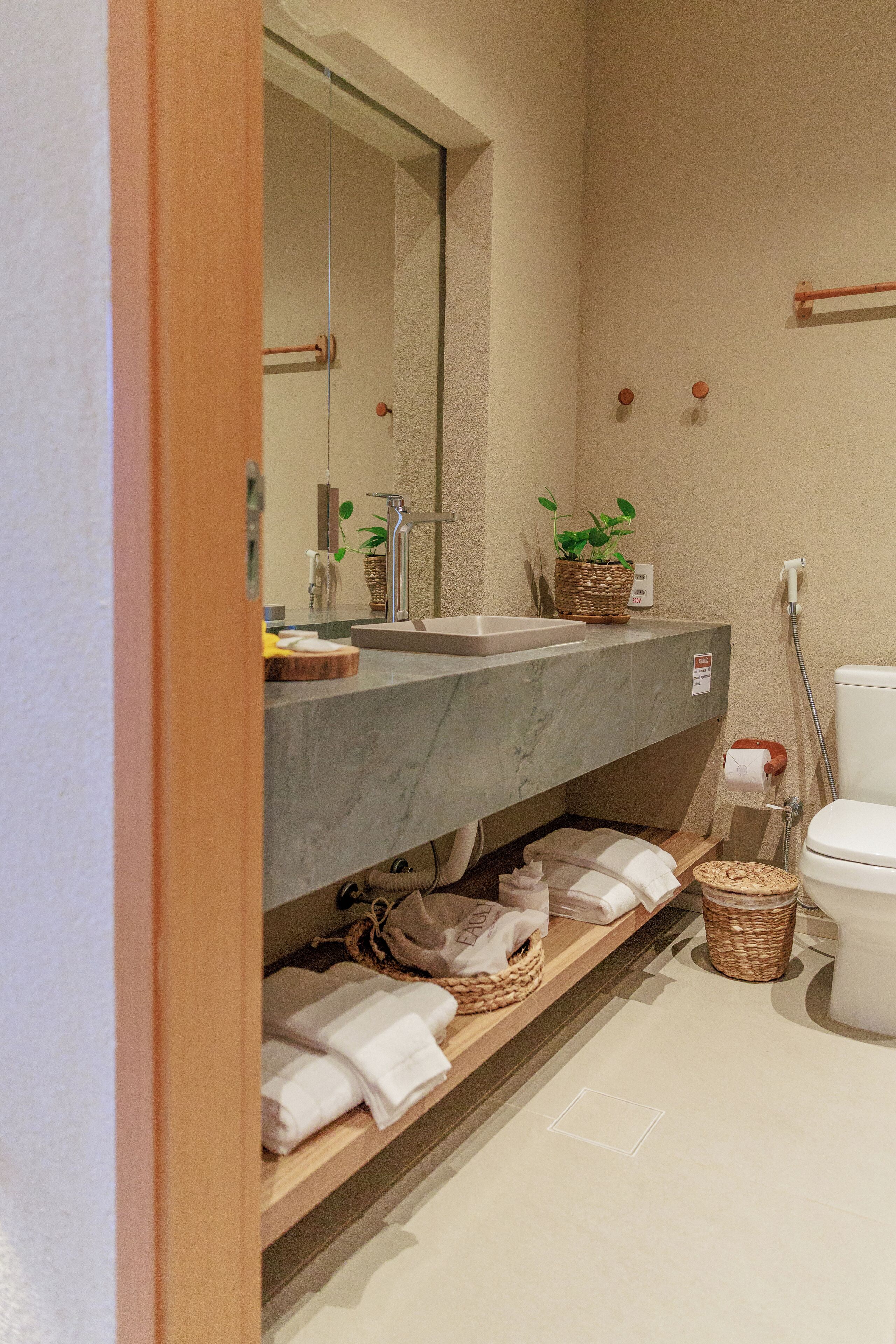 A modern bathroom with a marble sink, a mirror, a toilet, and a shower area.