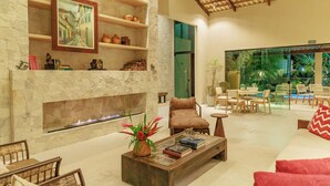 Amplia sala de estar con chimenea de piedra, asientos cómodos y vistas al exterior.