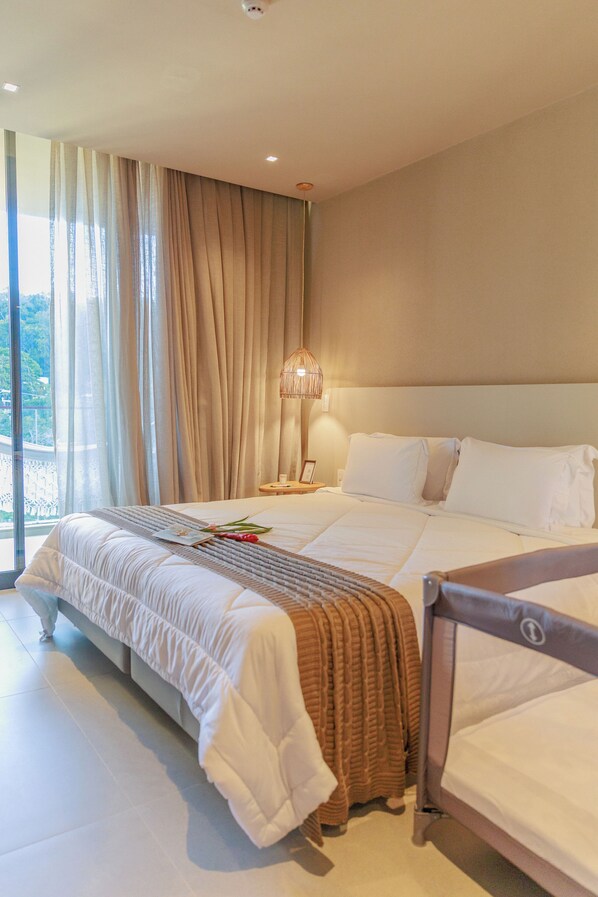 A hotel room with a large bed, a bedside table with a lamp, and a view of the outdoors. - Eagle Boutique Hotel (Guaramiranga)