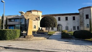 Une cour ornée d’une sculpture en pierre, d’un arbre aux branches soigneusement taillées et d’un bâtiment surmonté d’un toit en tuiles.