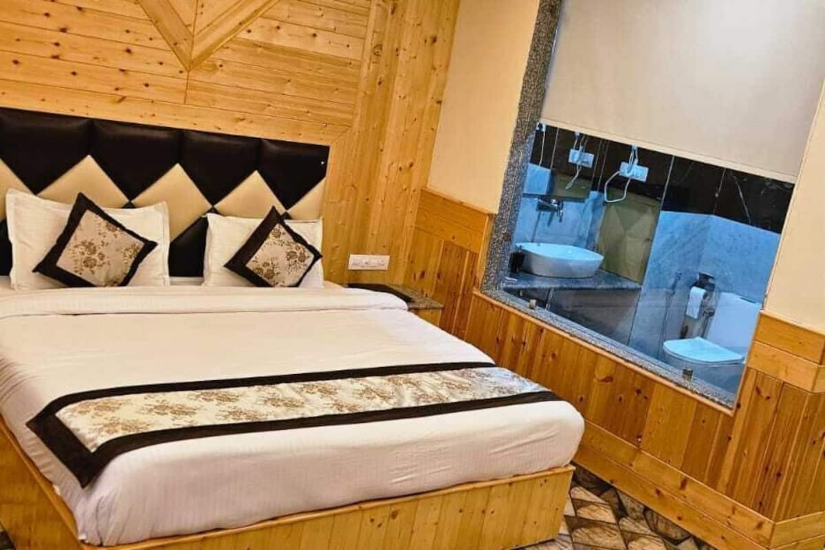 A wooden-paneled bedroom with a bed, nightstand, and a bathroom visible through a window.