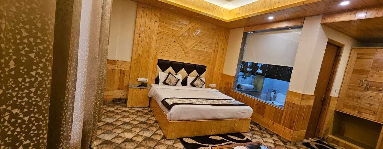 A bedroom with a wooden headboard, a bed with a patterned bedspread, a nightstand, and a window with a view of the outside.