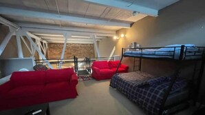 A dorm-style room with bunk beds, a red sofa, and a small table. - Condo Great for Large Family (Sandusky)