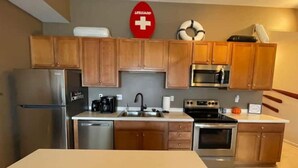 A modern kitchen with wooden cabinets, stainless steel appliances, and a lifeguard sign on the wall. - Condo Great for Large Family (Sandusky)