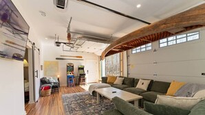 Ein geräumiges Wohnzimmer mit einem grünen Sofa, einem Couchtisch und einer Spielecke mit Spielautomaten.