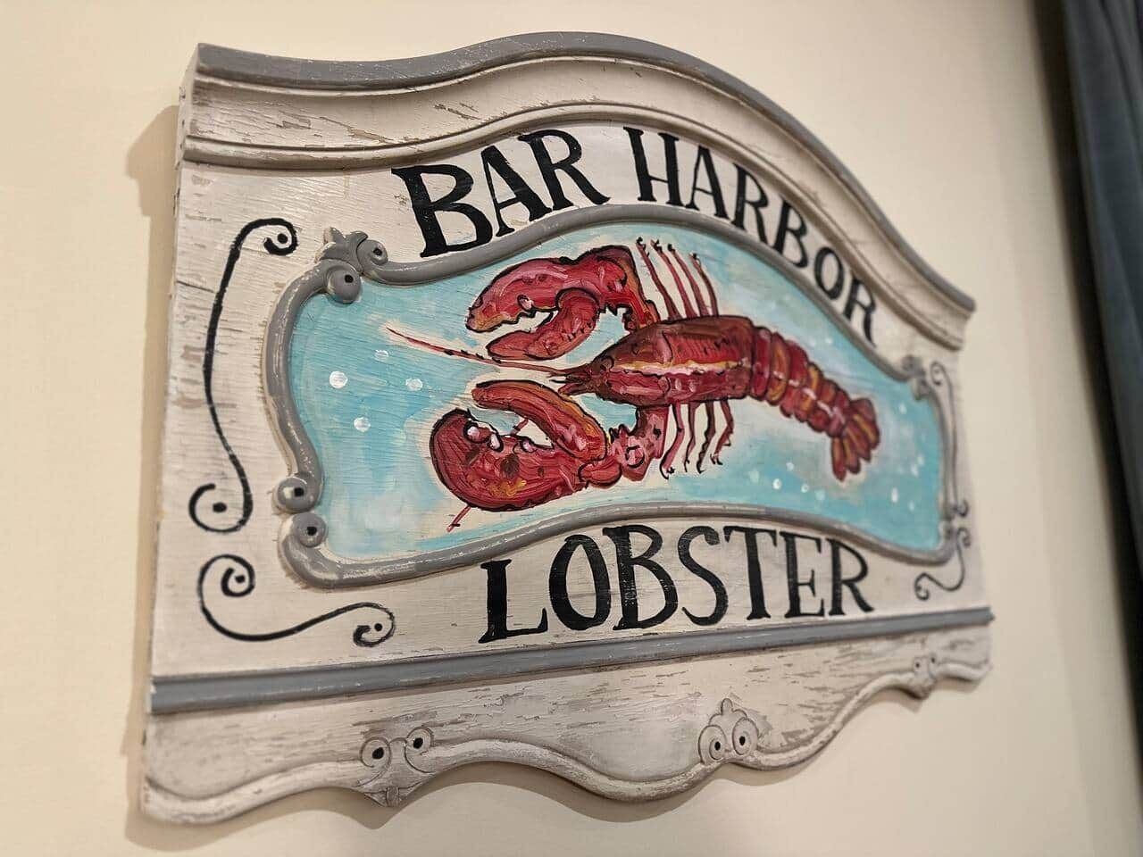 Une enseigne murale avec l’inscription « BAR HARBOUR LOBSTER » et une illustration de homard.