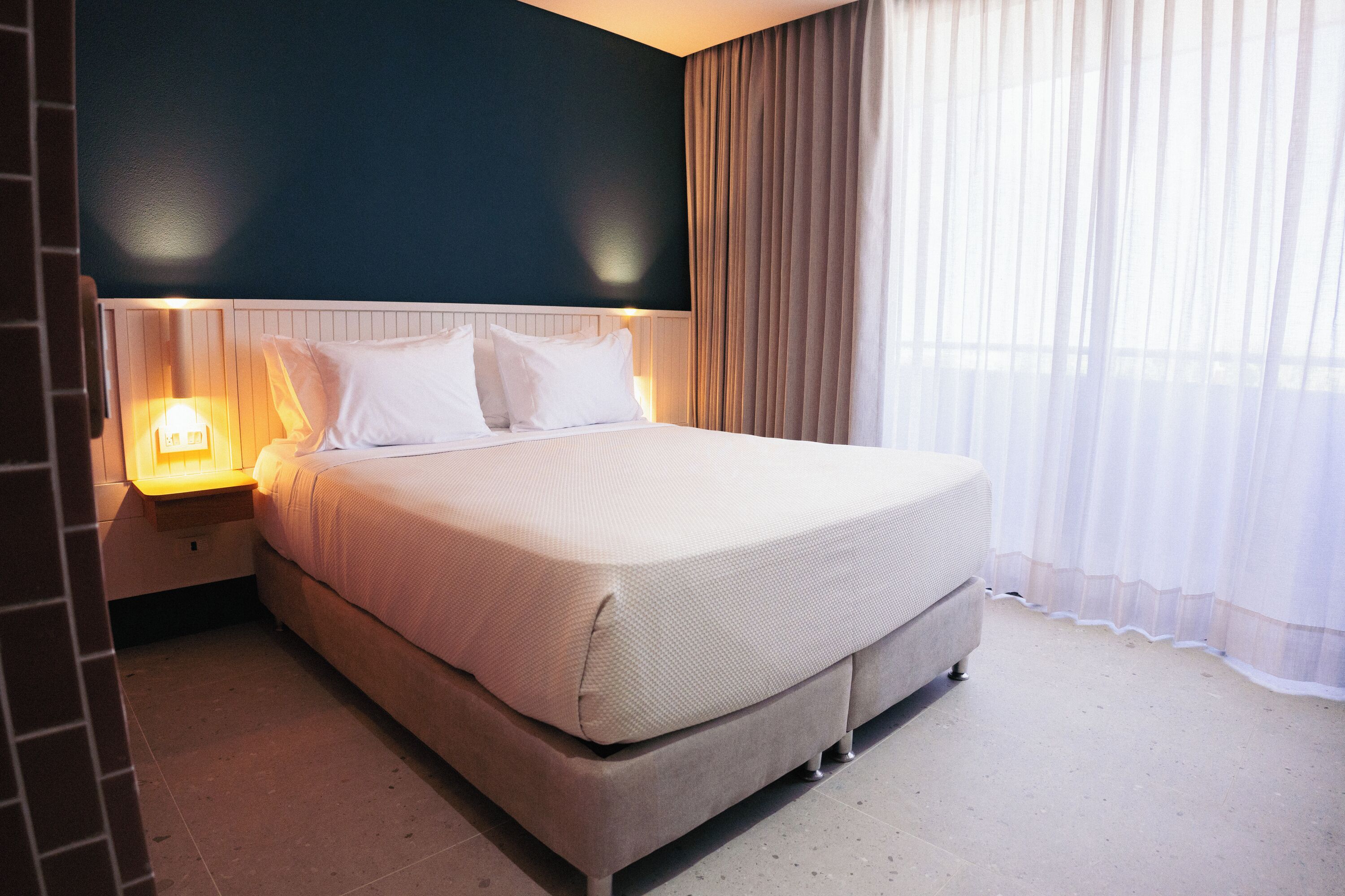 A neatly made bed with white linens in a hotel room.