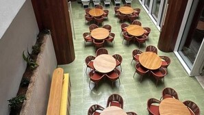 A courtyard with multiple round tables and chairs, surrounded by wooden pillars and a white fence. - Zapadilly Tree Hotel (San Andres)