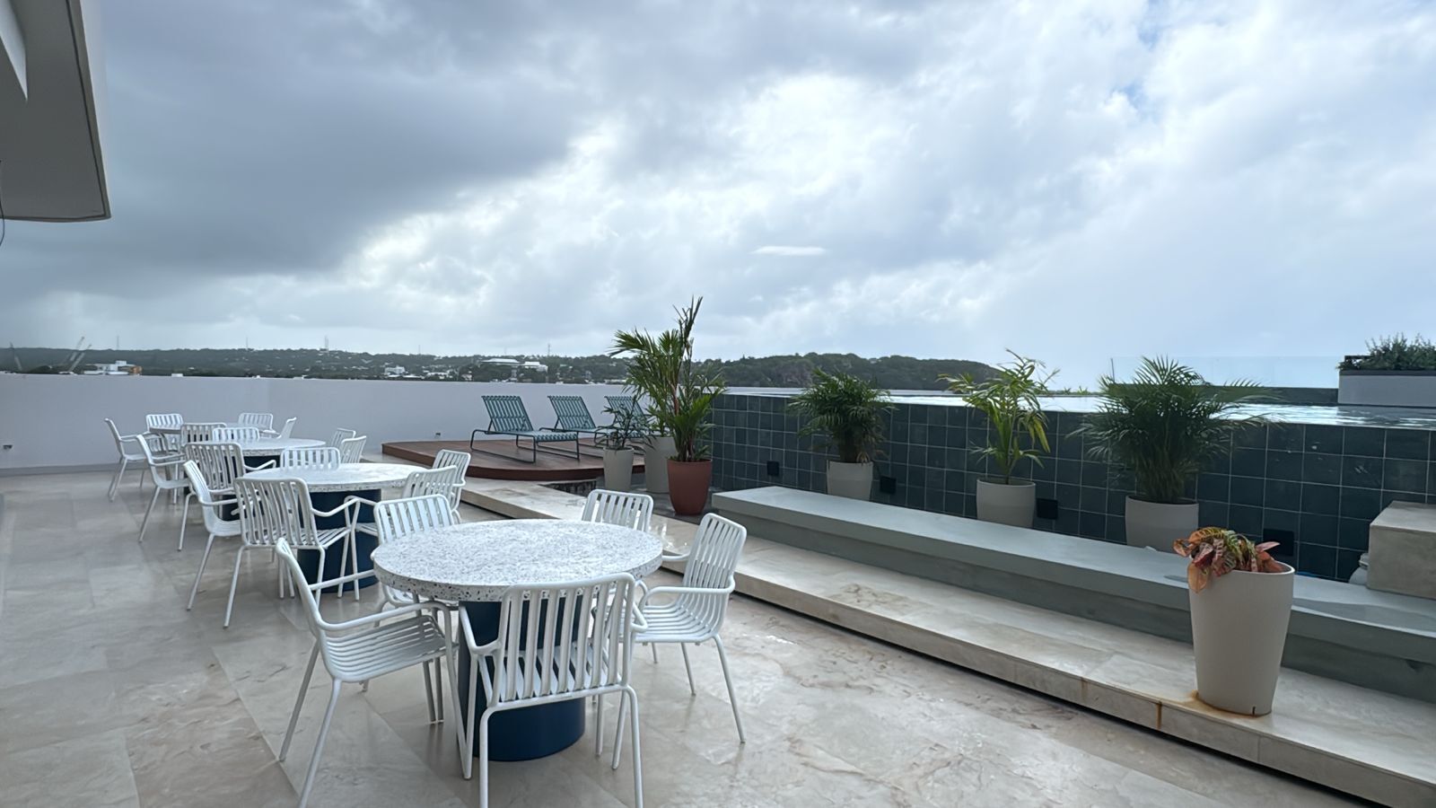A rooftop terrace with outdoor seating, potted plants, and a view of the cityscape.