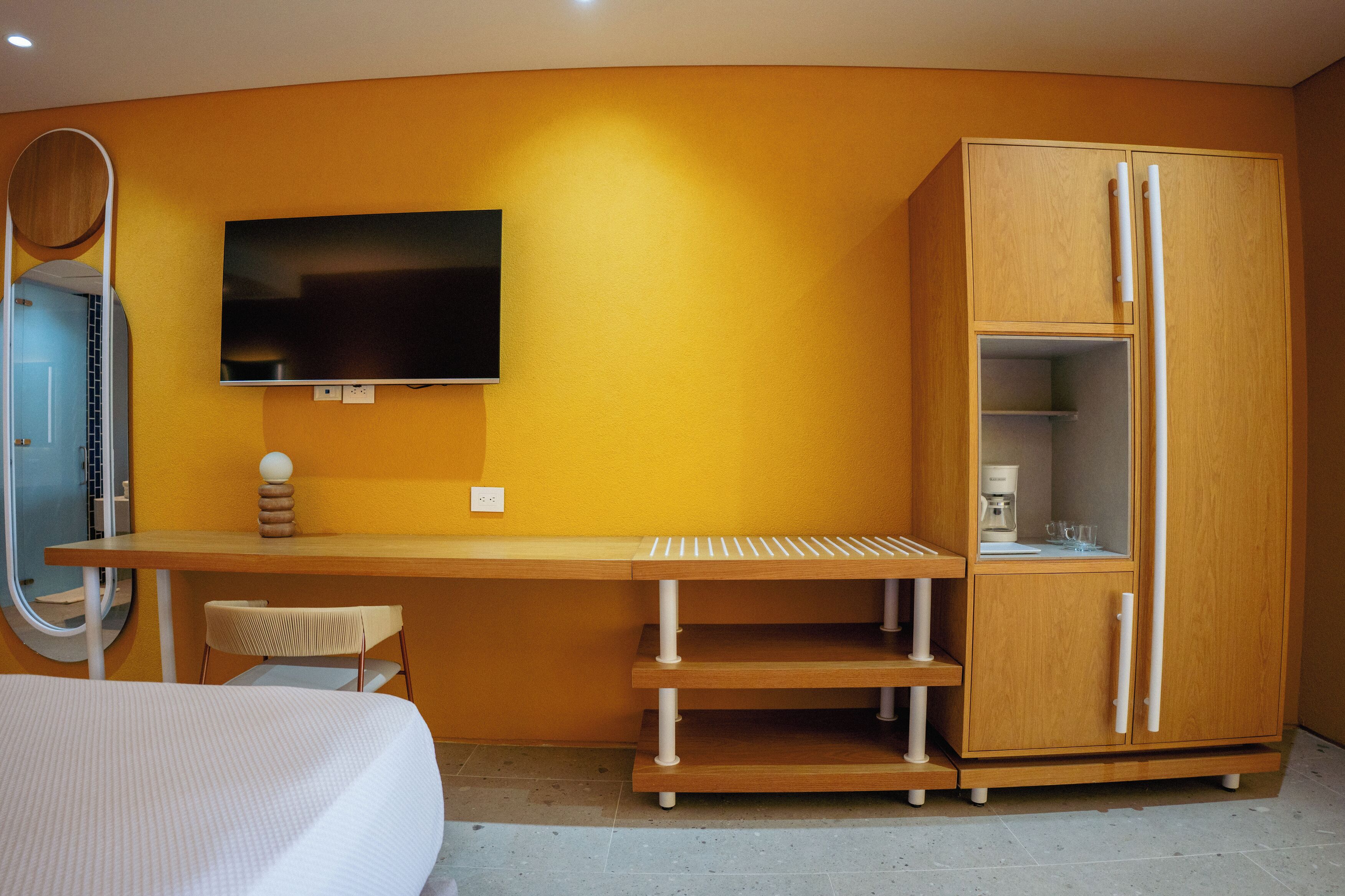 A modern bedroom with a bed, a desk, a TV, and a wardrobe.