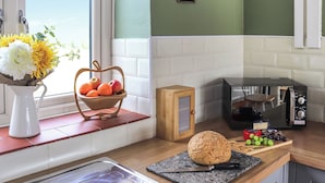 Eine Küche mit Toaster, Brot, Schneidebrett mit Trauben, Obstkorb und Blumenvase.