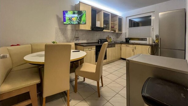 A compact kitchen with a dining area, a built-in TV, and a refrigerator.