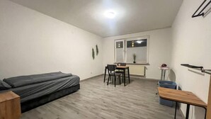 A compact room with a bed, a small table, a chair, and a window.