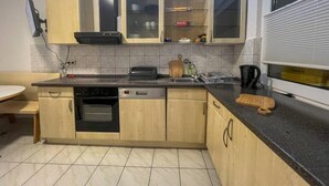 A kitchen with wooden cabinets, a built-in oven, a dishwasher, and a black countertop.