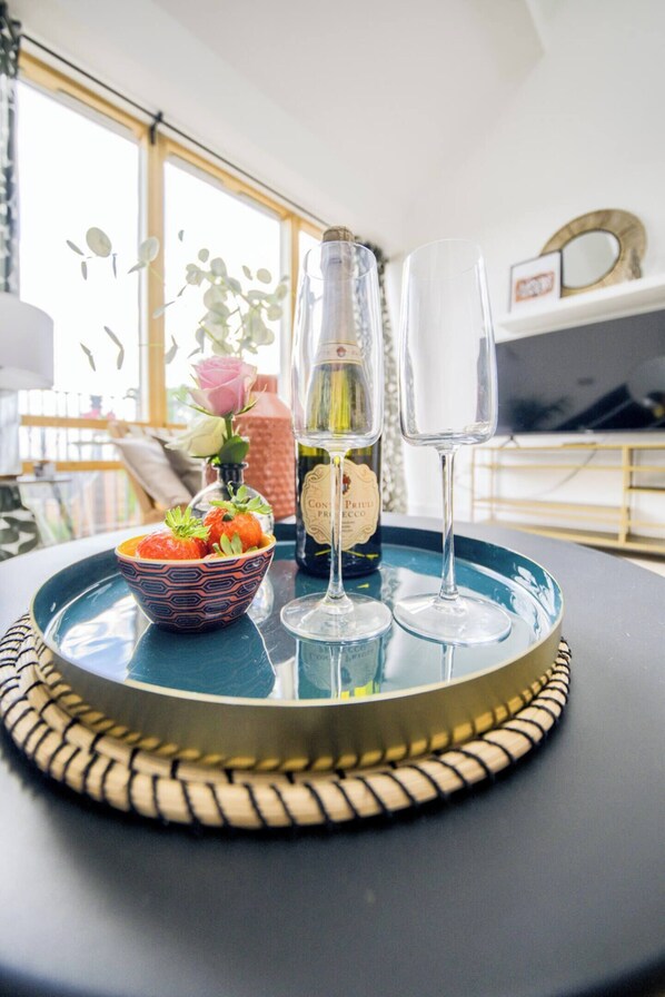 A tray with a bottle of wine, two glasses, and a bowl of strawberries on a table.