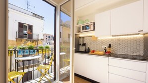 A modern kitchen with white cabinets, a microwave, and a hexagonal tile backsplash. - Appartamenti Pellegrino (Palermo)