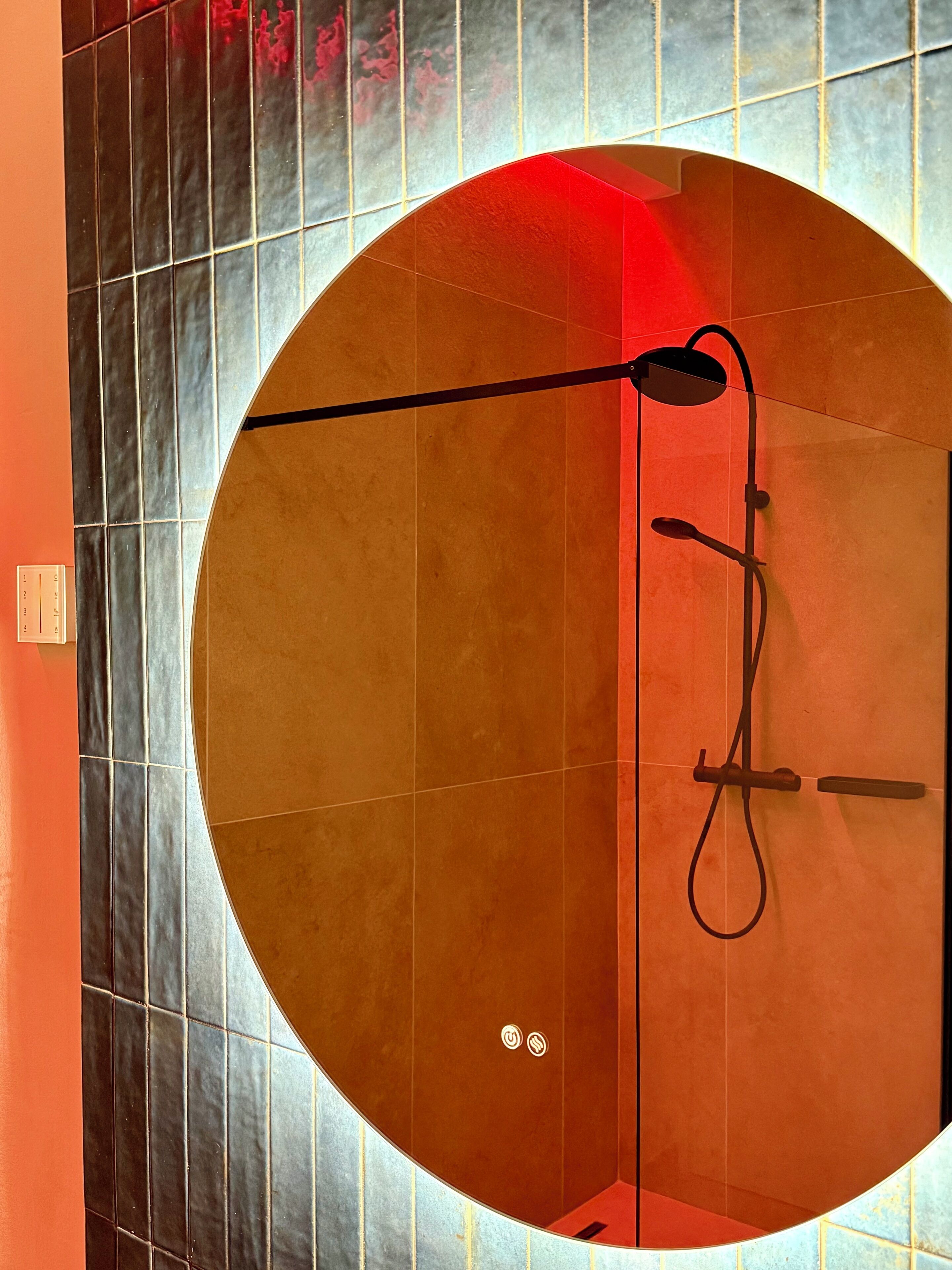 A circular shower area with a modern design, featuring a handheld showerhead and a fixed showerhead.