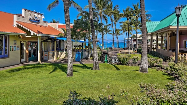 Un hôtel situé en bord de mer, doté d’un espace extérieur couvert, de palmiers et offrant une vue sur l’océan.