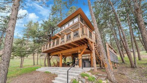A wooden cabin with a balcony, built into a forest setting.