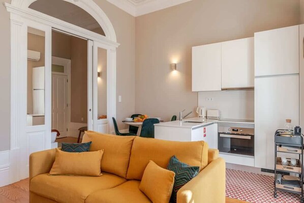 A compact living space with a sofa, kitchenette, and a dining area.