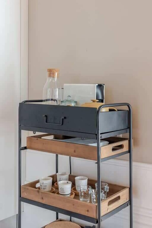 A metal bunk bed with a wooden lower shelf, a small table, and a bottle on the top bunk.