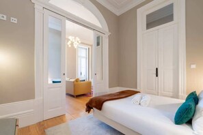 Un dormitorio con una cama, una puerta que da a otra habitación y un pasillo.
