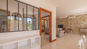 A spacious living area with a stone wall, a large window, and a television.
