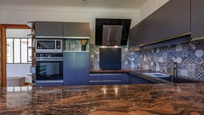 A modern kitchen with granite countertops, a built-in oven, microwave, and a stainless steel range hood.