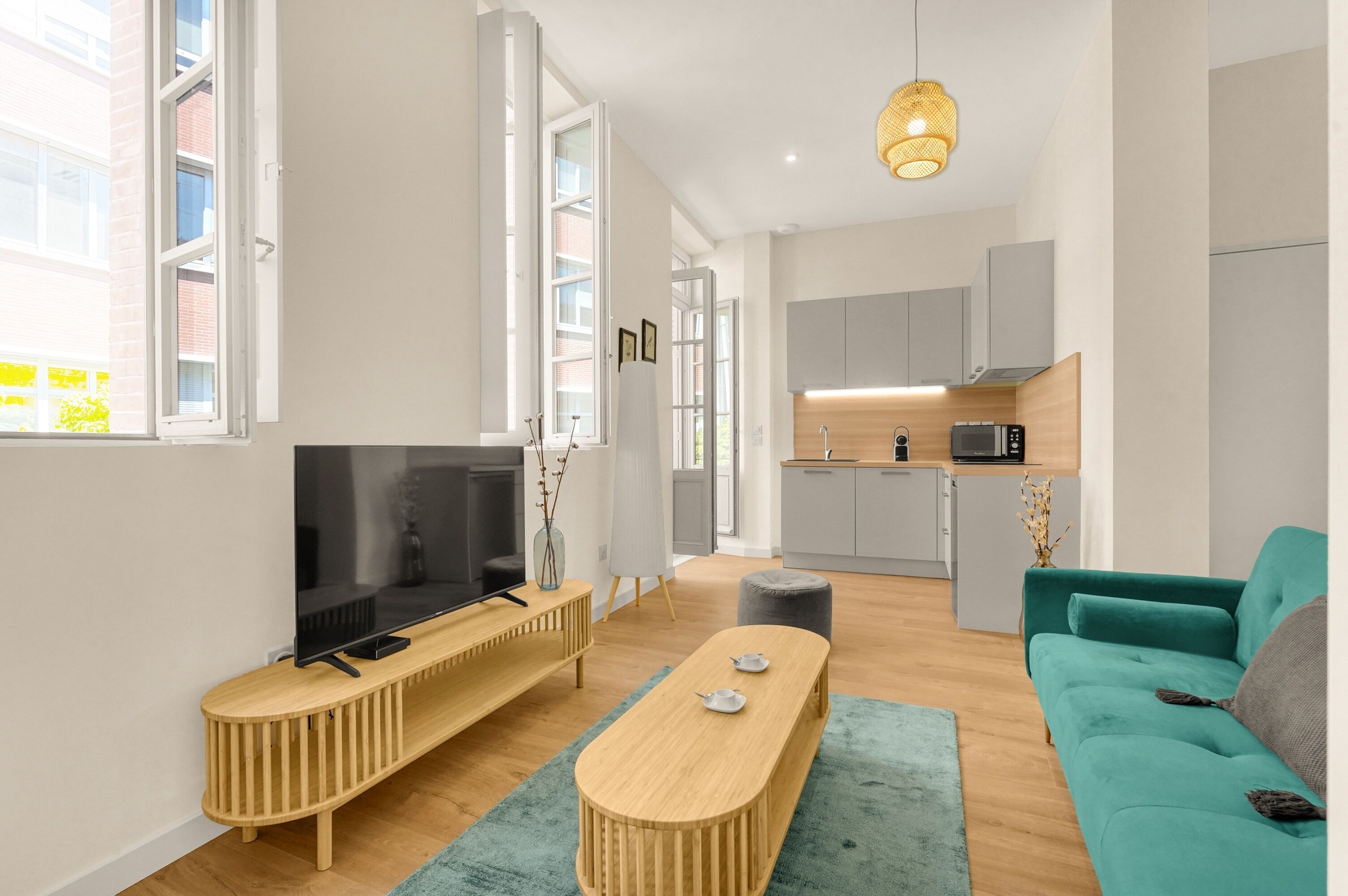 A modern living room with a TV, wooden entertainment unit, and a teal sofa.