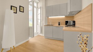 A modern kitchen with grey cabinets, a wooden countertop, and a built-in microwave. There is a window with a view of the outside. - Bloom - 12min à pied du Capitole (Toulouse)