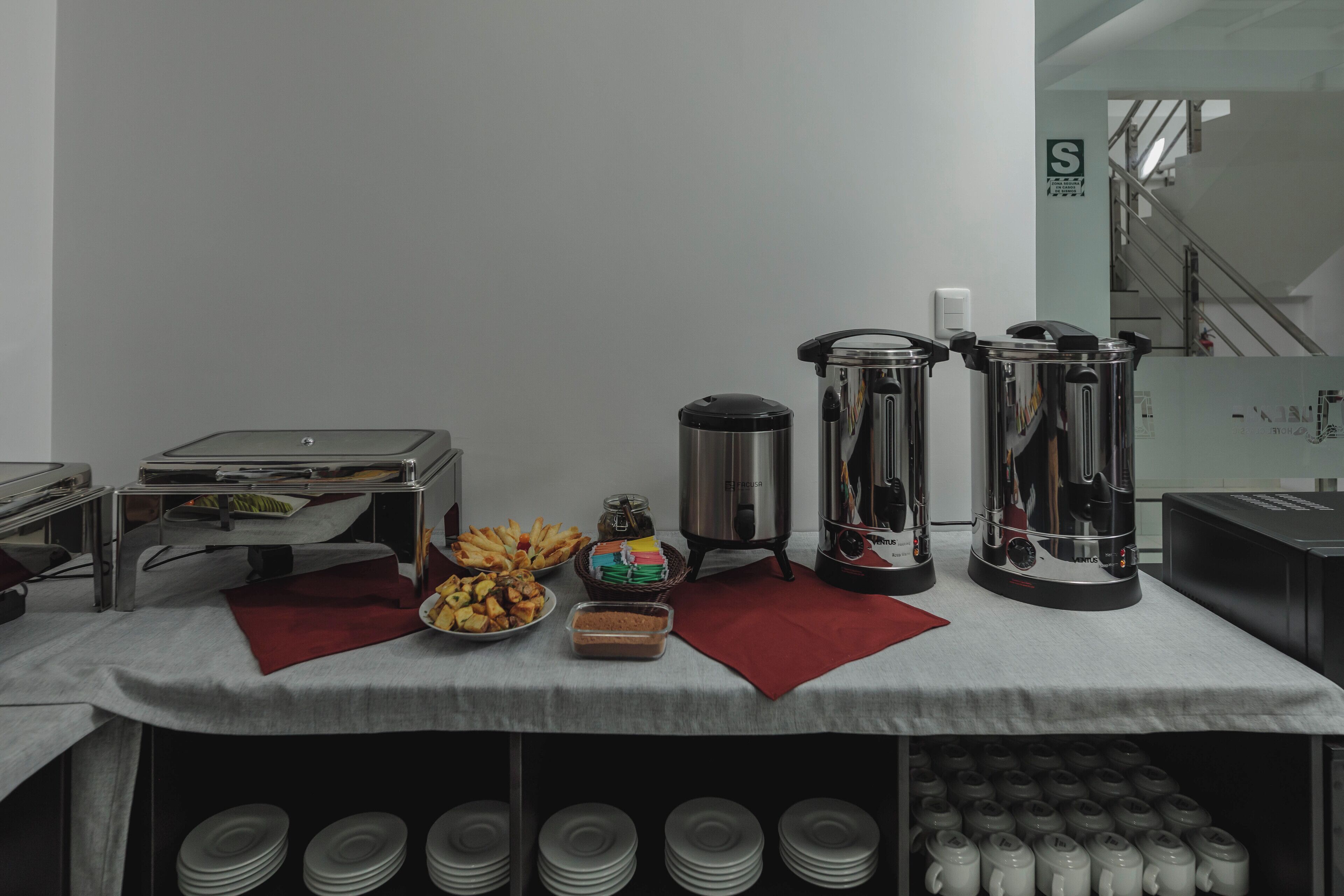 A buffet setup with various food items, a coffee station, and a stack of plates.