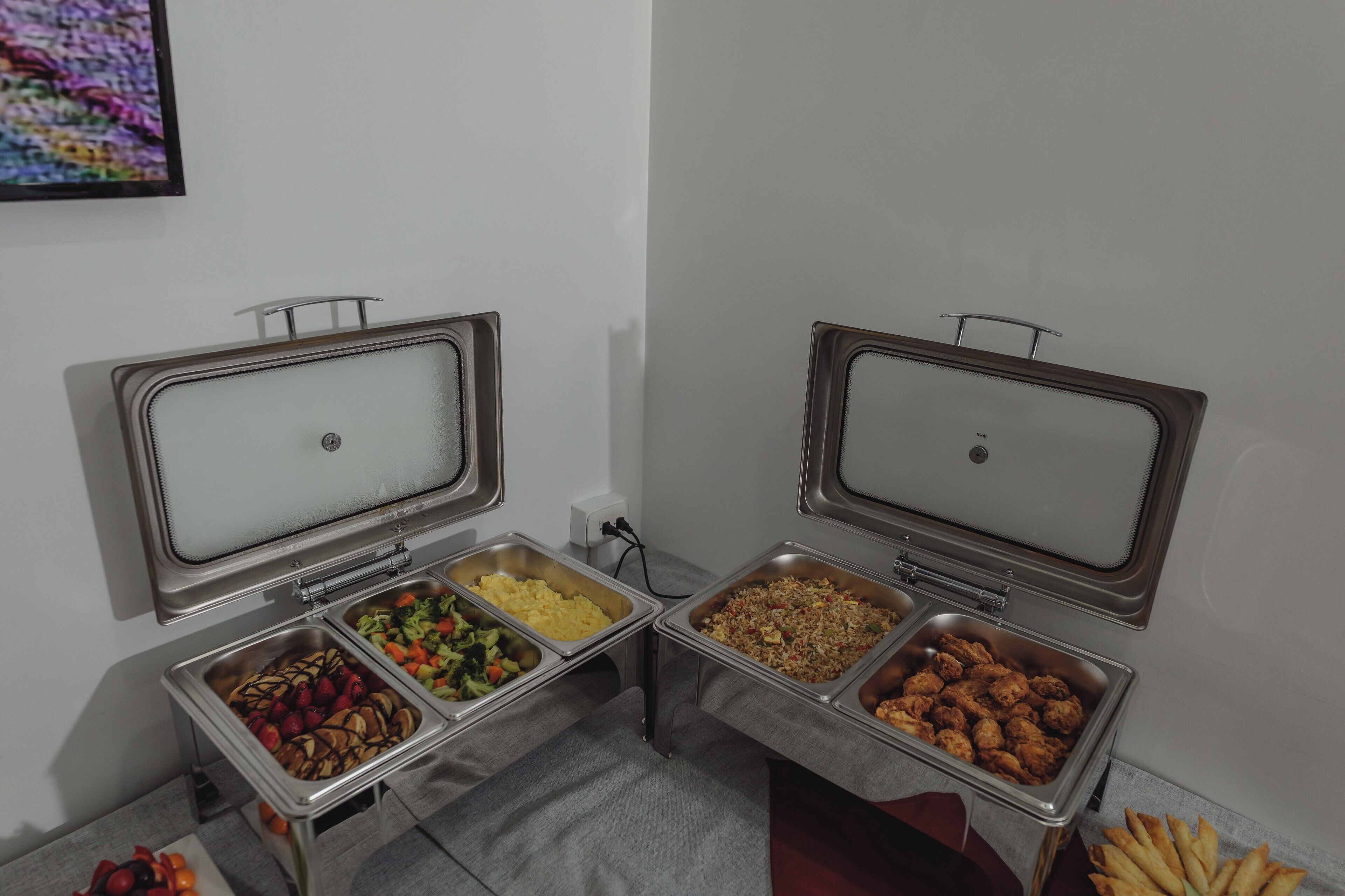 Un bufé con diversas opciones de comida, incluyendo frutas, verduras y alimentos fritos.