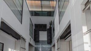 Un interior moderno con techo de vidrio, barandillas de metal y una escalera central.