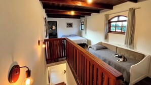 Une pièce chaleureuse avec un escalier en bois, un lit, une fenêtre avec des rideaux et un luminaire fixé au mur.