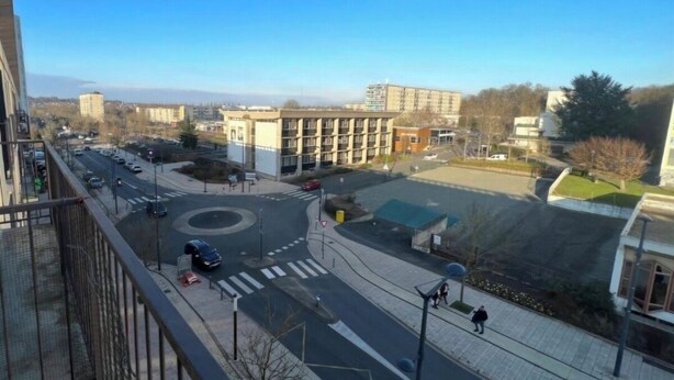 A cityscape with a roundabout, buildings, and a pedestrian walkway. - Private room (Allonnes)