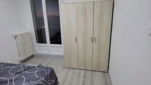 A bedroom with a bed, a wardrobe, a radiator, and a window with a view. - Private room (Allonnes)
