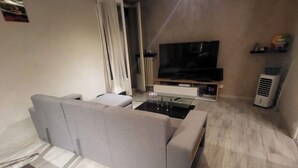 A modern living room with a grey sectional sofa, a flat-screen TV, and a glass coffee table. - Private room (Allonnes)