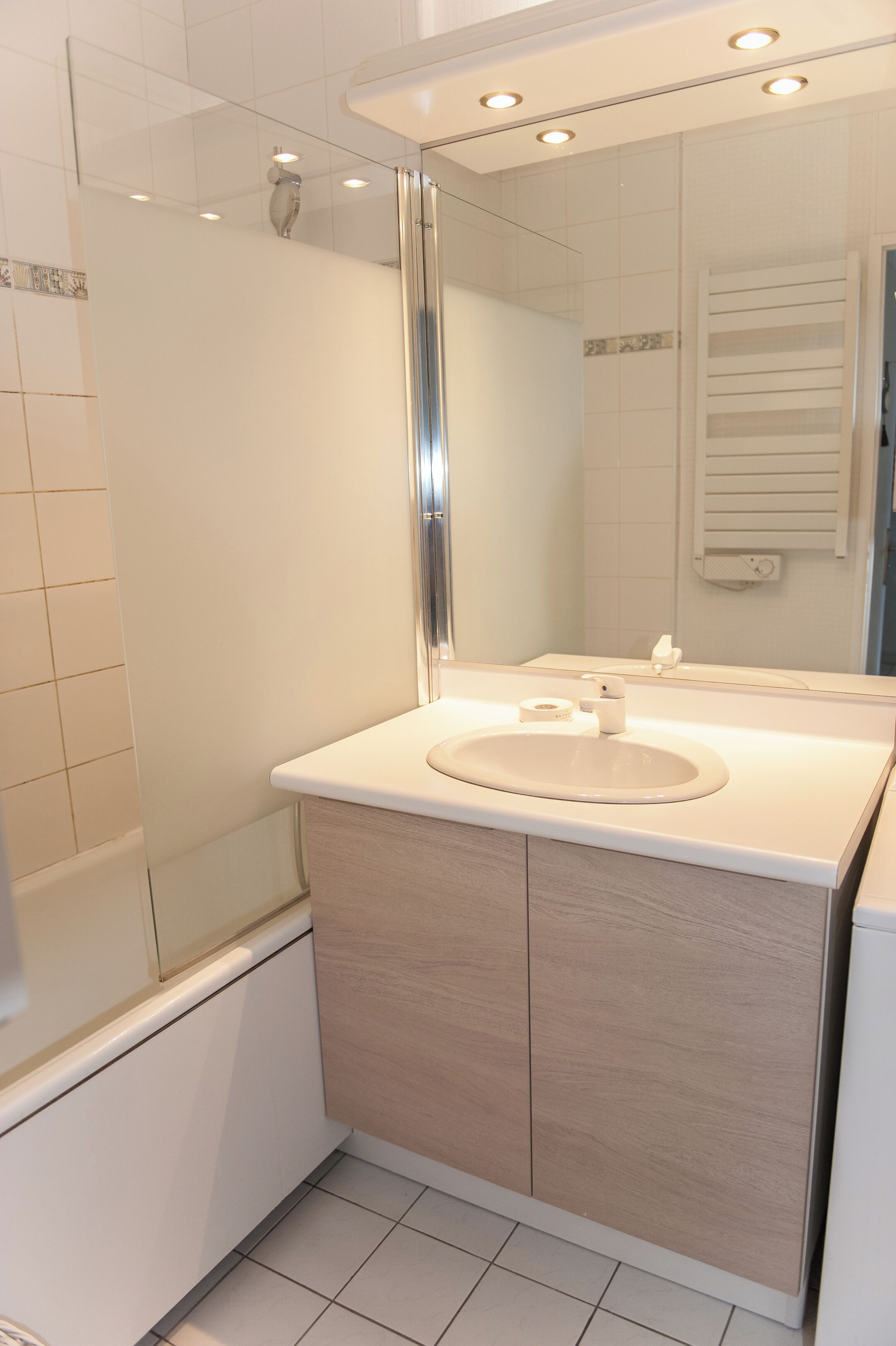 A modern bathroom with a white sink, mirror, and shower.