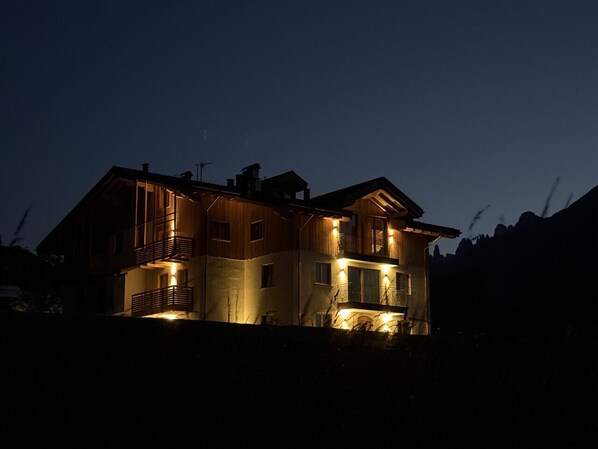 A multi-story house with balconies and a lit exterior at dusk. - Appartamento Erica Andalo (Andalo)