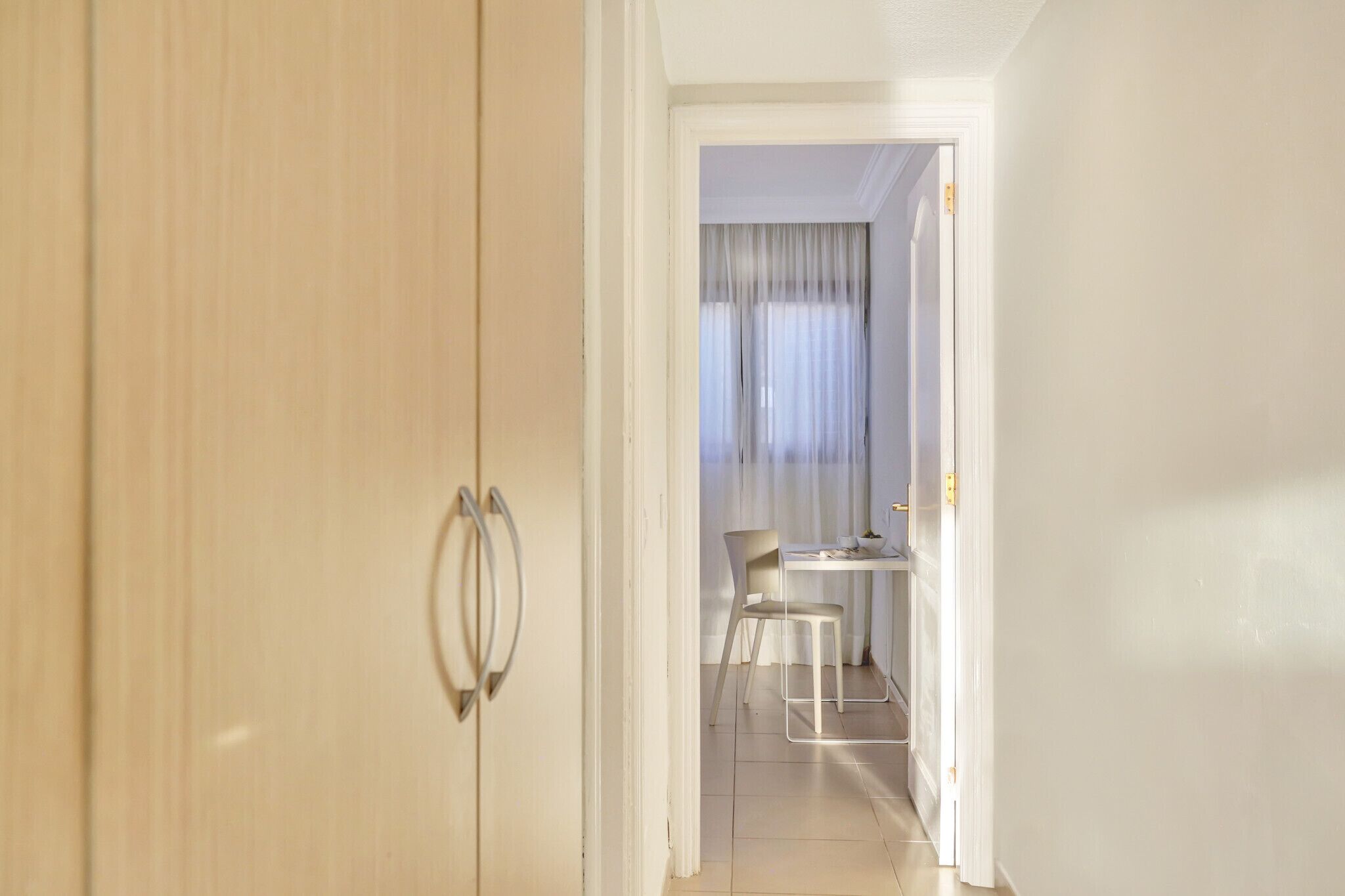 A hallway leading to a dining area with a table and chairs.