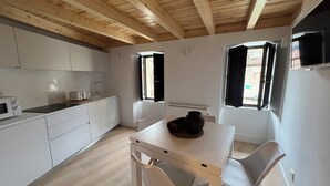 Een moderne keuken met witte kasten, een magnetron en een eethoek met een tafel en stoelen.