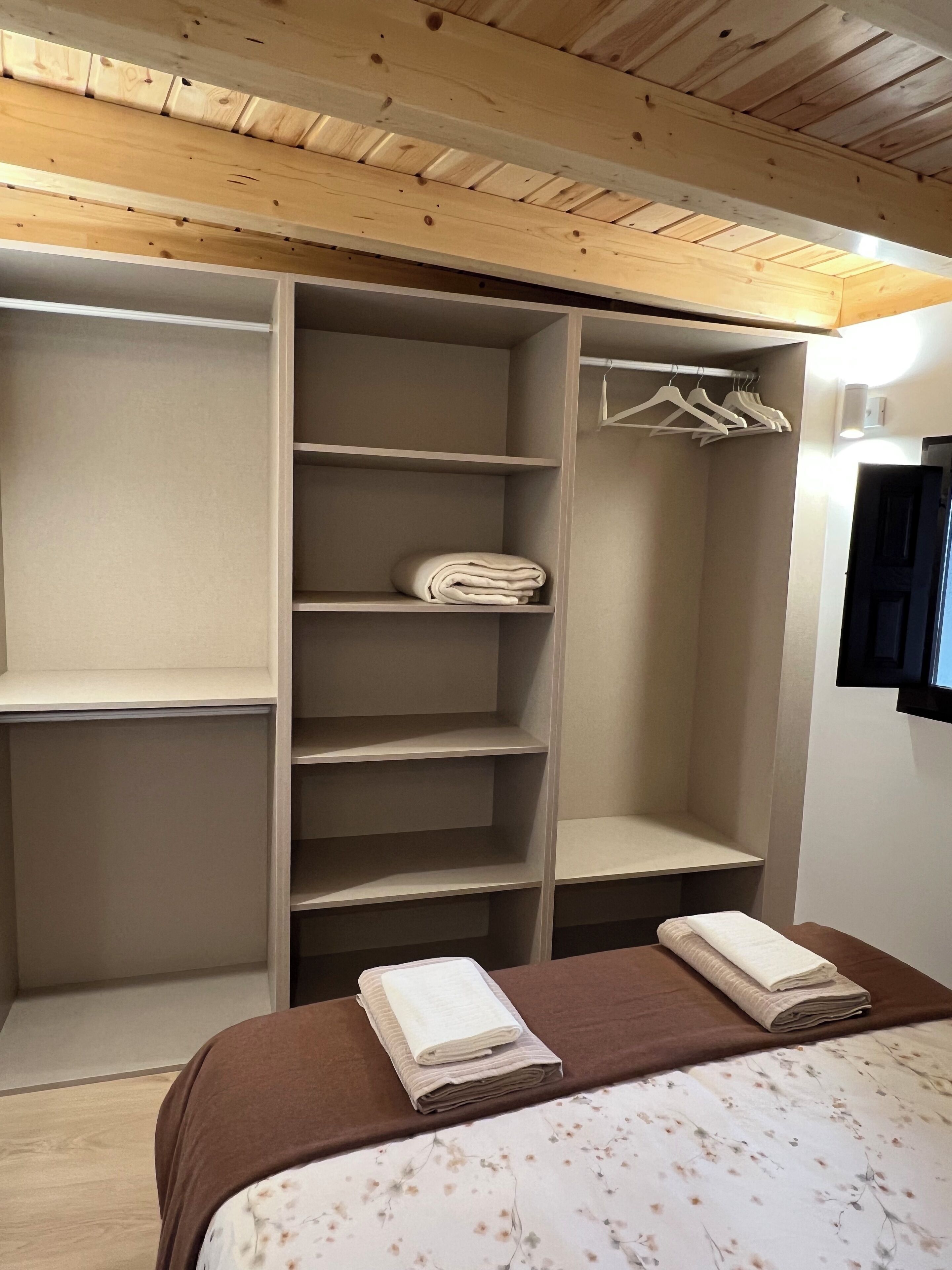 A bedroom with a bed, a wardrobe, and a hanging closet.