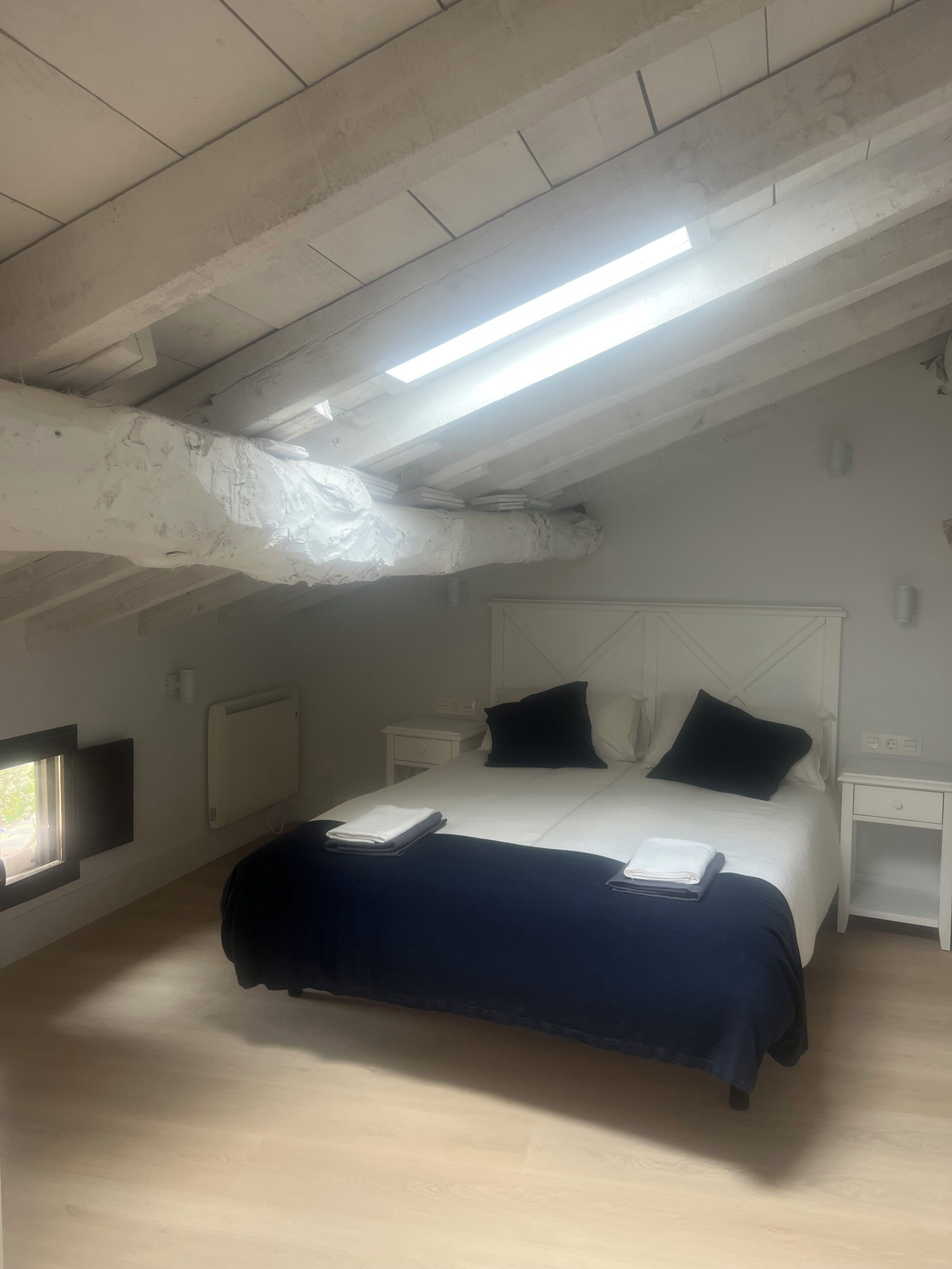 A bedroom with a bed, bedside tables, a window, and a ceiling light.
