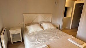 Een slaapkamer met een groot bed, een nachtkastje, een radiator en een houten plafond.