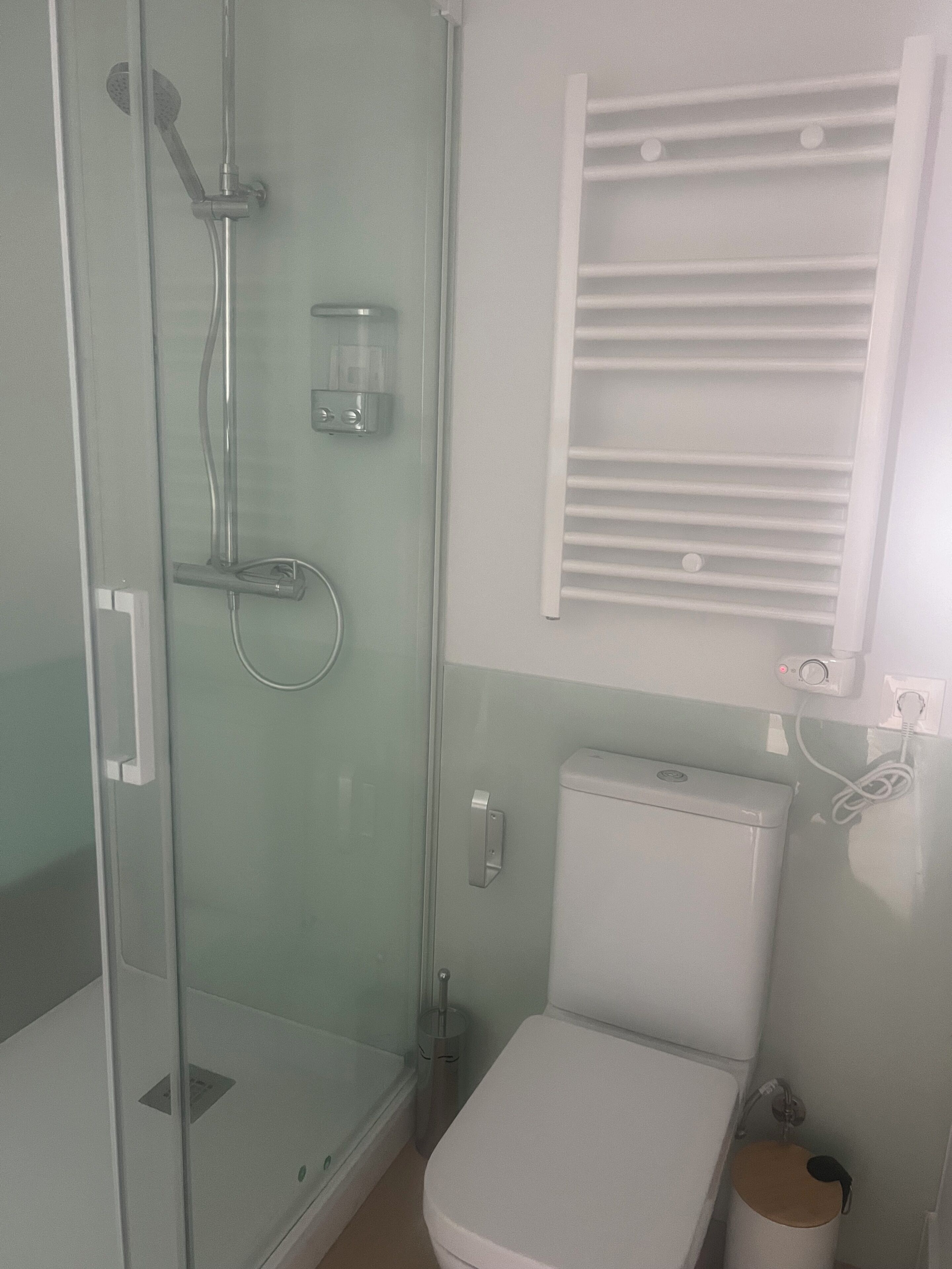 Une salle de bain avec une douche à parois de verre, des toilettes et une fenêtre équipée de stores.