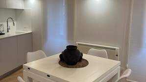 Een moderne keuken met witte kasten, een wit aanrecht en een houten plafond.