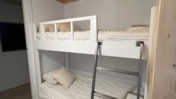 Een slaapkamer met een stapelbed, houten plafond en een metalen ladder.