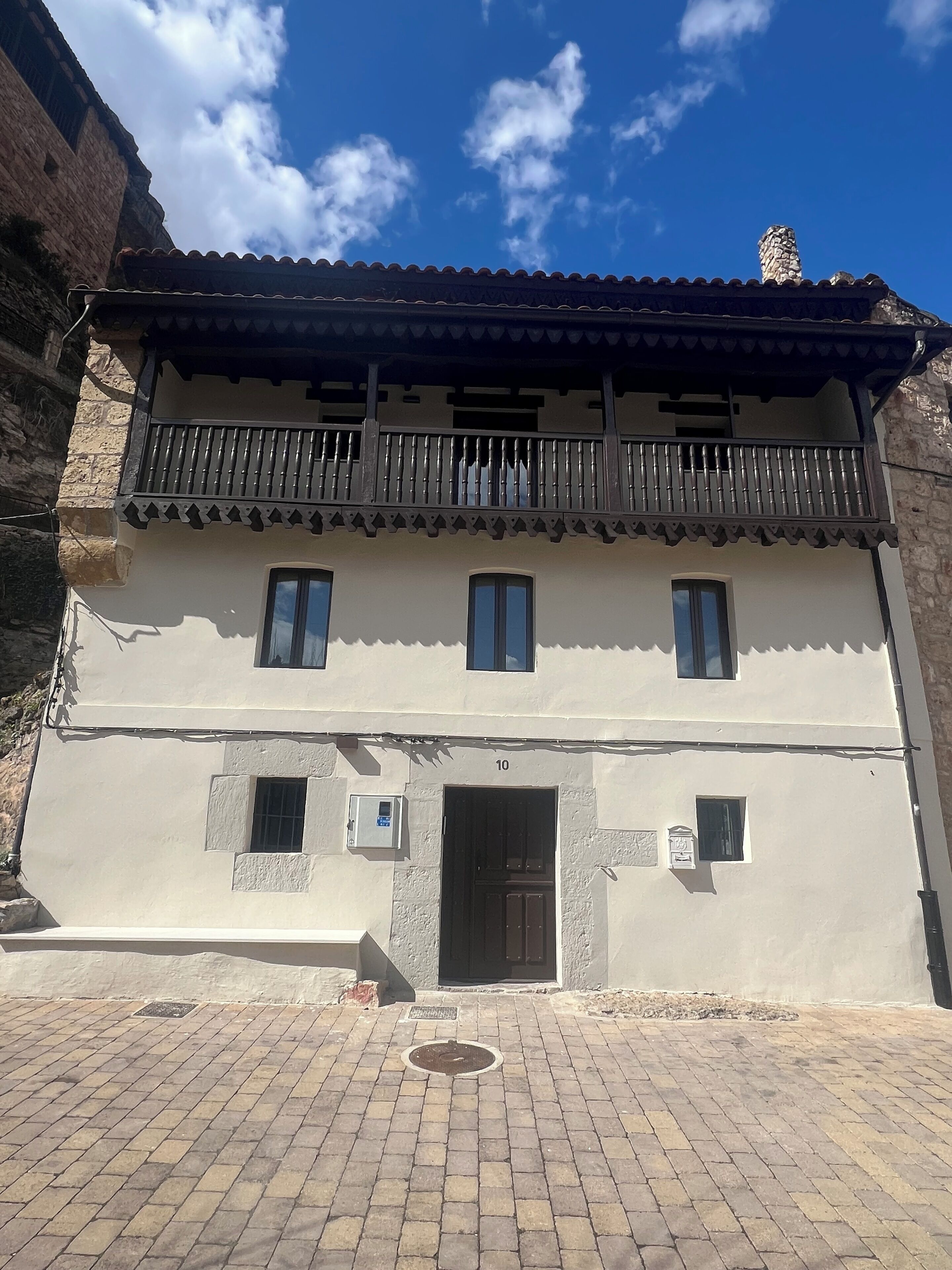 A two-story building with a balcony, a door, and a small window.