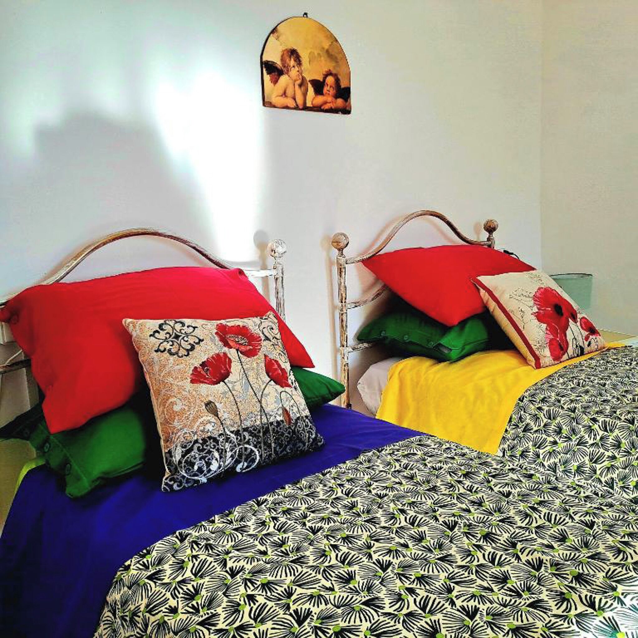 A bedroom with two beds, each with colorful bedding and decorative pillows.