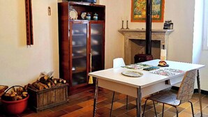 Un espace repas comprenant une table, des chaises, un téléviseur, une cheminée et un meuble contenant des objets décoratifs.